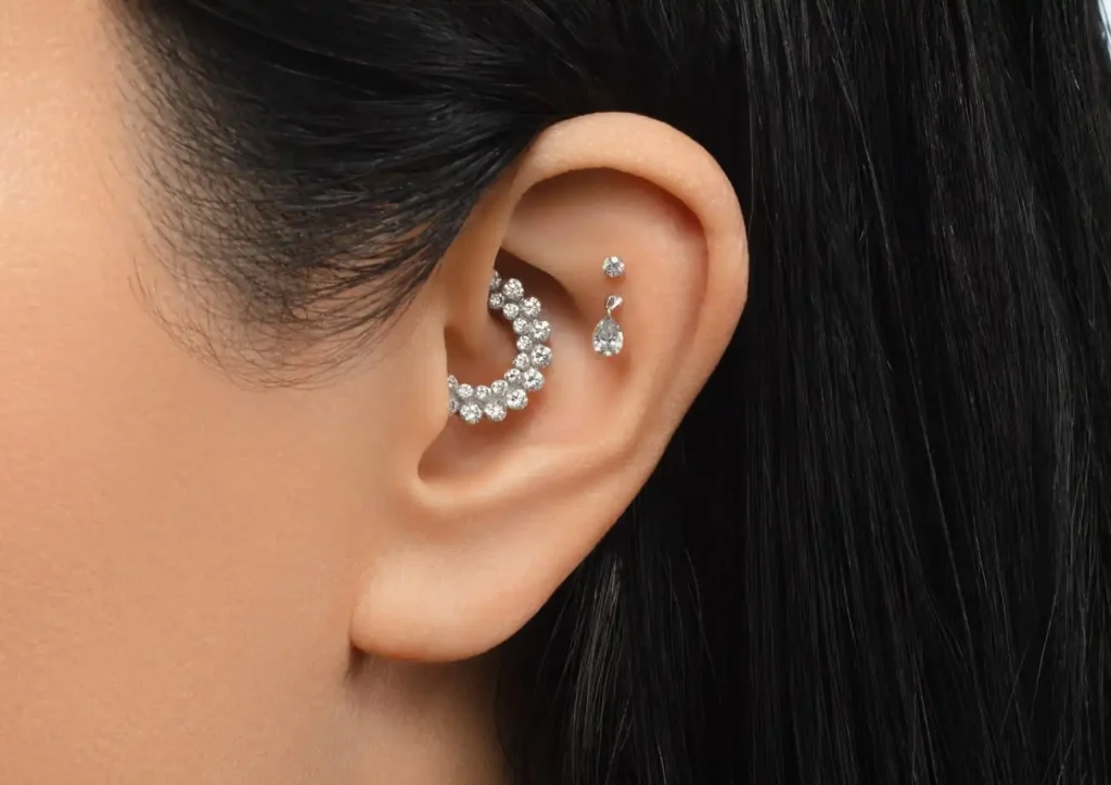 Close-up of a silver daith piercing with a sparkling gemstone, showcasing intricate craftsmanship and elegant design.