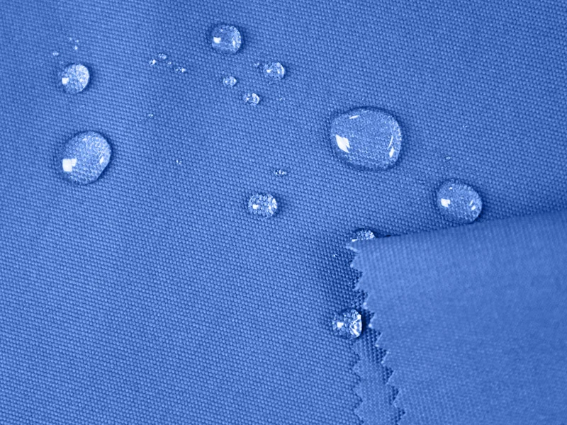 Close-up image of water droplets sliding off a piece of water-resistant fabric, highlighting its protective coating and repellent properties.